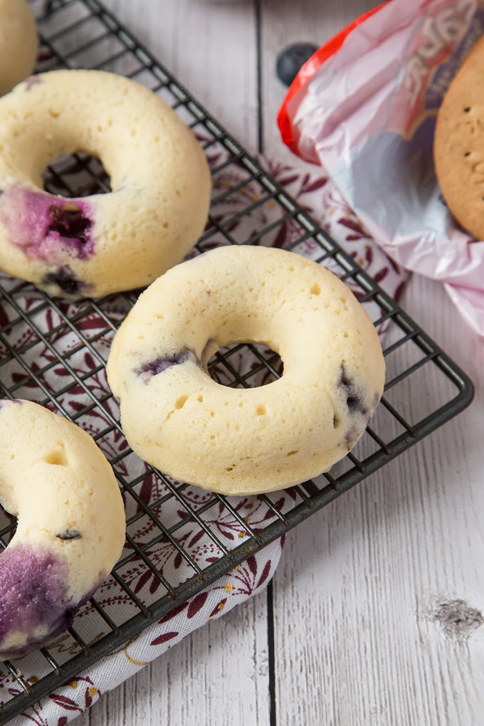 These Baked Blueberry Cheesecake Doughnuts are filled with juicy blueberries and topped with the most amazing cream cheese frosting and biscuit crumbs.