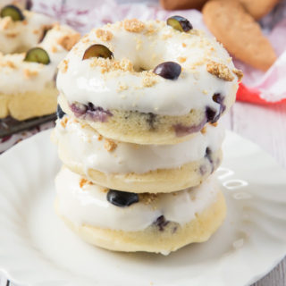 These Baked Blueberry Cheesecake Doughnuts are filled with juicy blueberries and topped with the most amazing cream cheese frosting and biscuit crumbs.