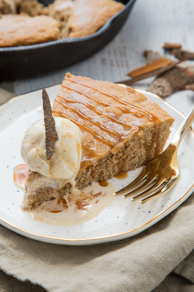 A thick and chewy snickerdoodle cake baked in a cast iron skillet and topped with ice cream and caramel sauce.