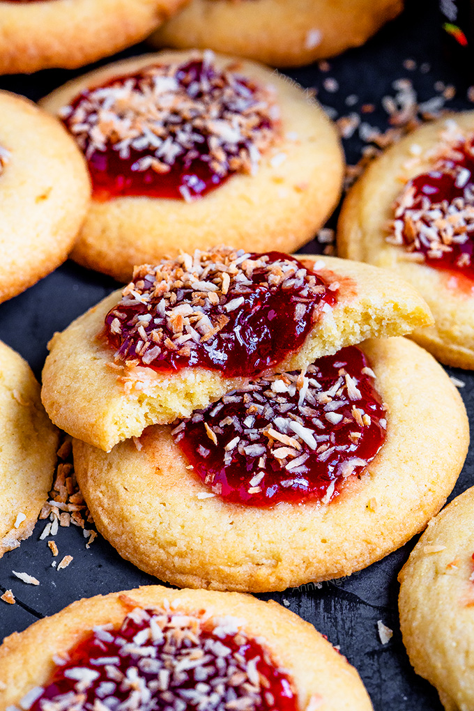 These Vegan Strawberry Coconut Thumbprint Cookies are so easy to make and taste amazing! Toasted coconut tops strawberry jam and a "buttery", cookie to make one bitesize delicious treat!